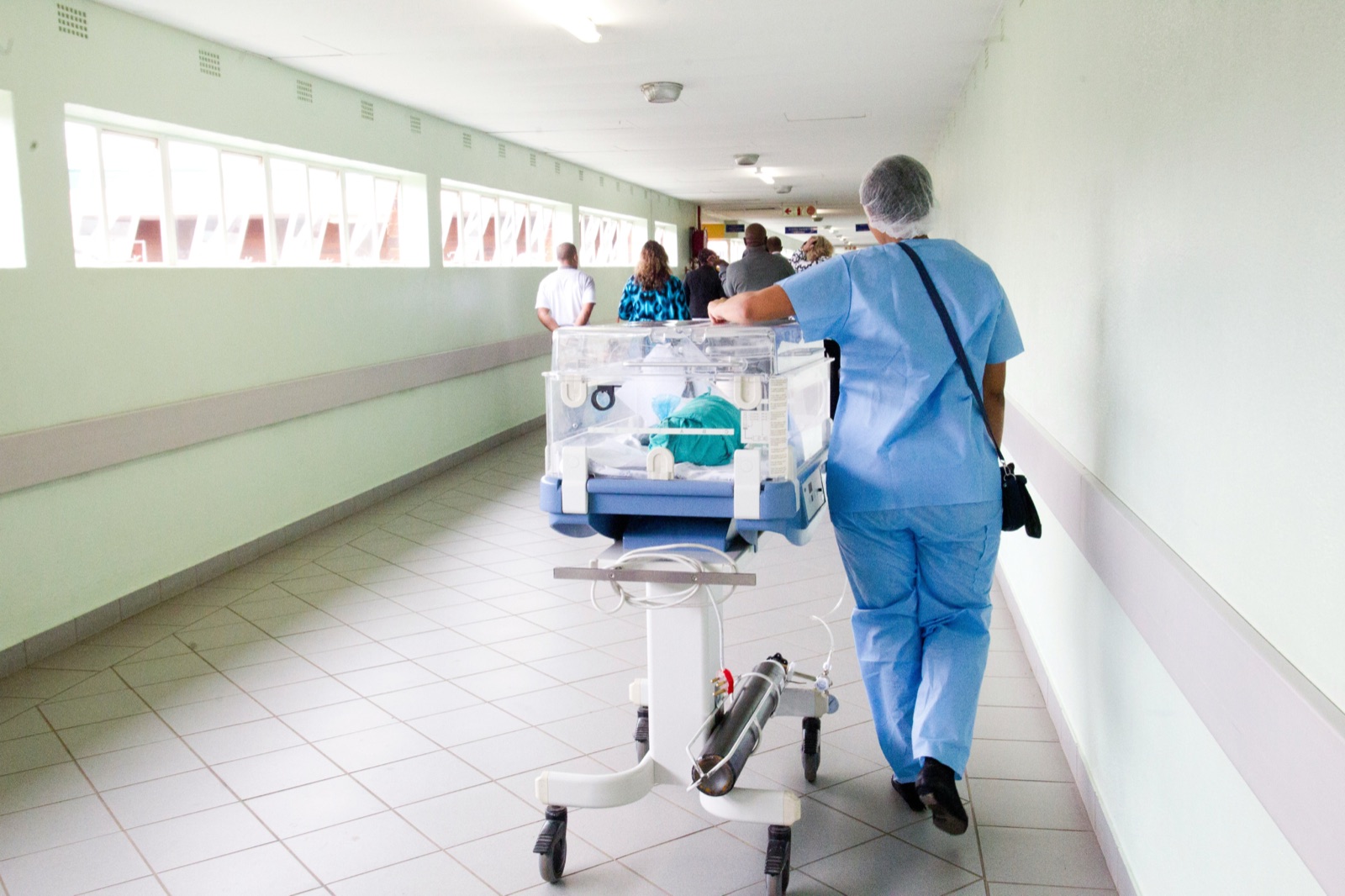 Nurses wheeling an incubator along a hospital corridor