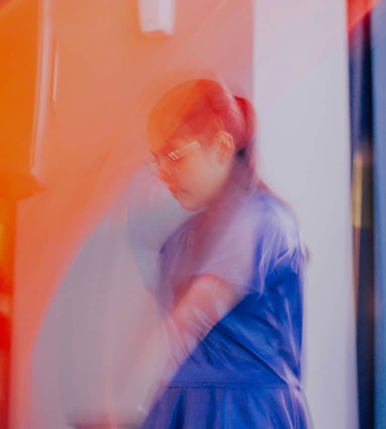A nurse in blue scrubs walking through a clinic corridor, in a blur of movement