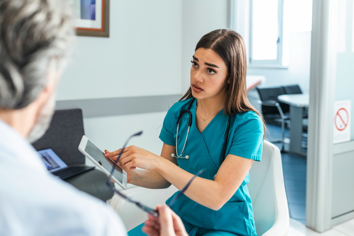 A nurse with a clipboard talking to a patient