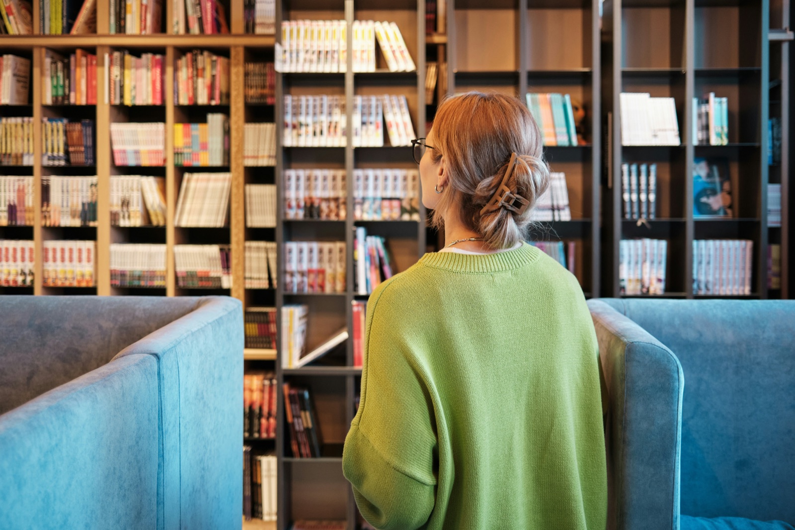 A student in a green top reading in a library